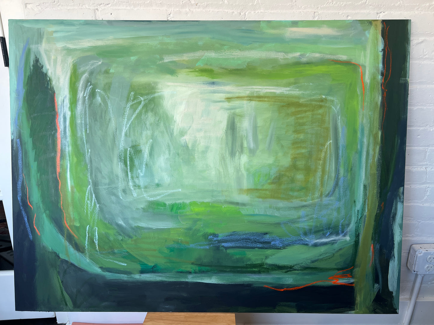 Abstract painting with green and blue tones on a white wall.