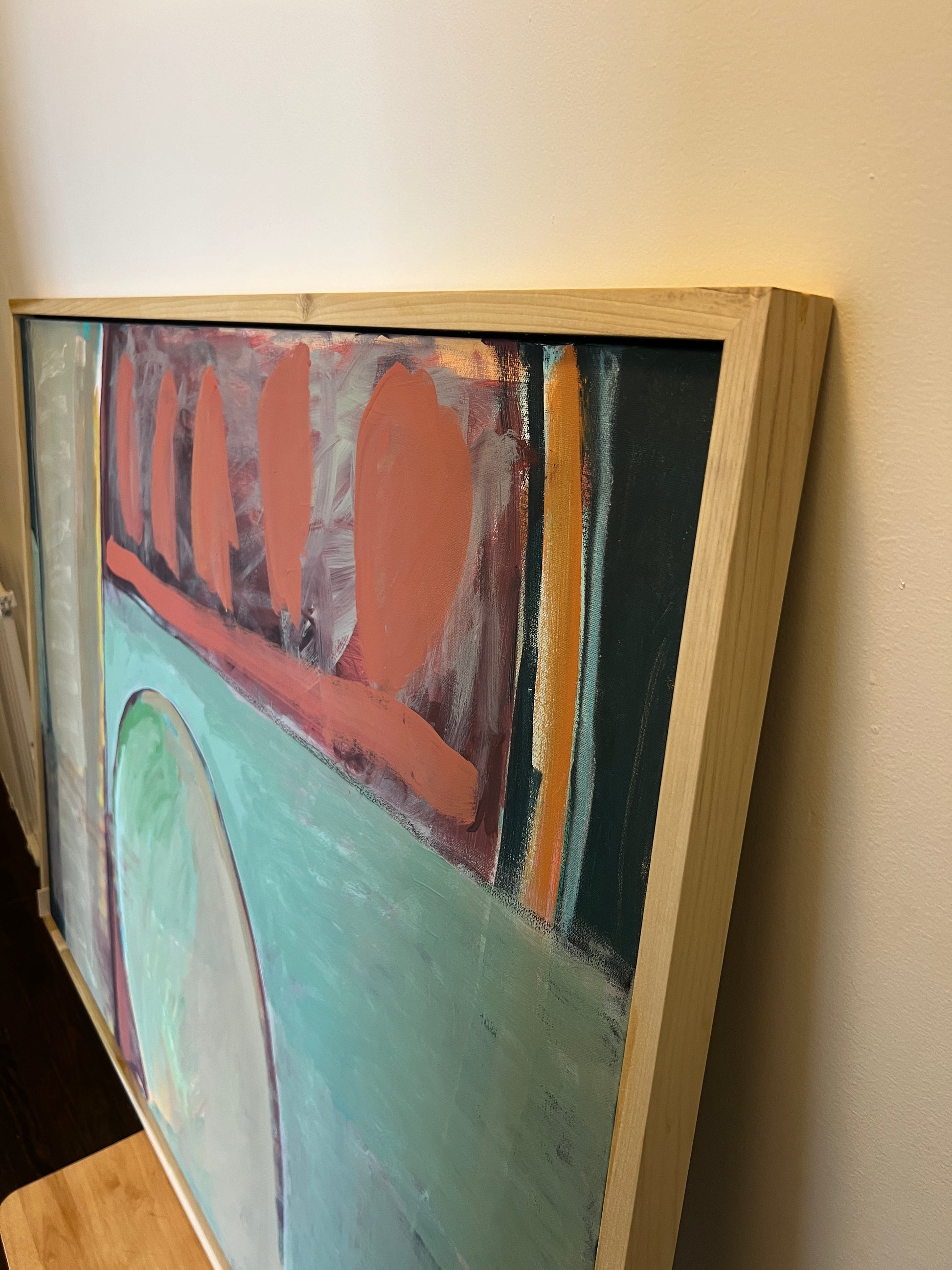 Abstract painting in a wooden frame on a wall.