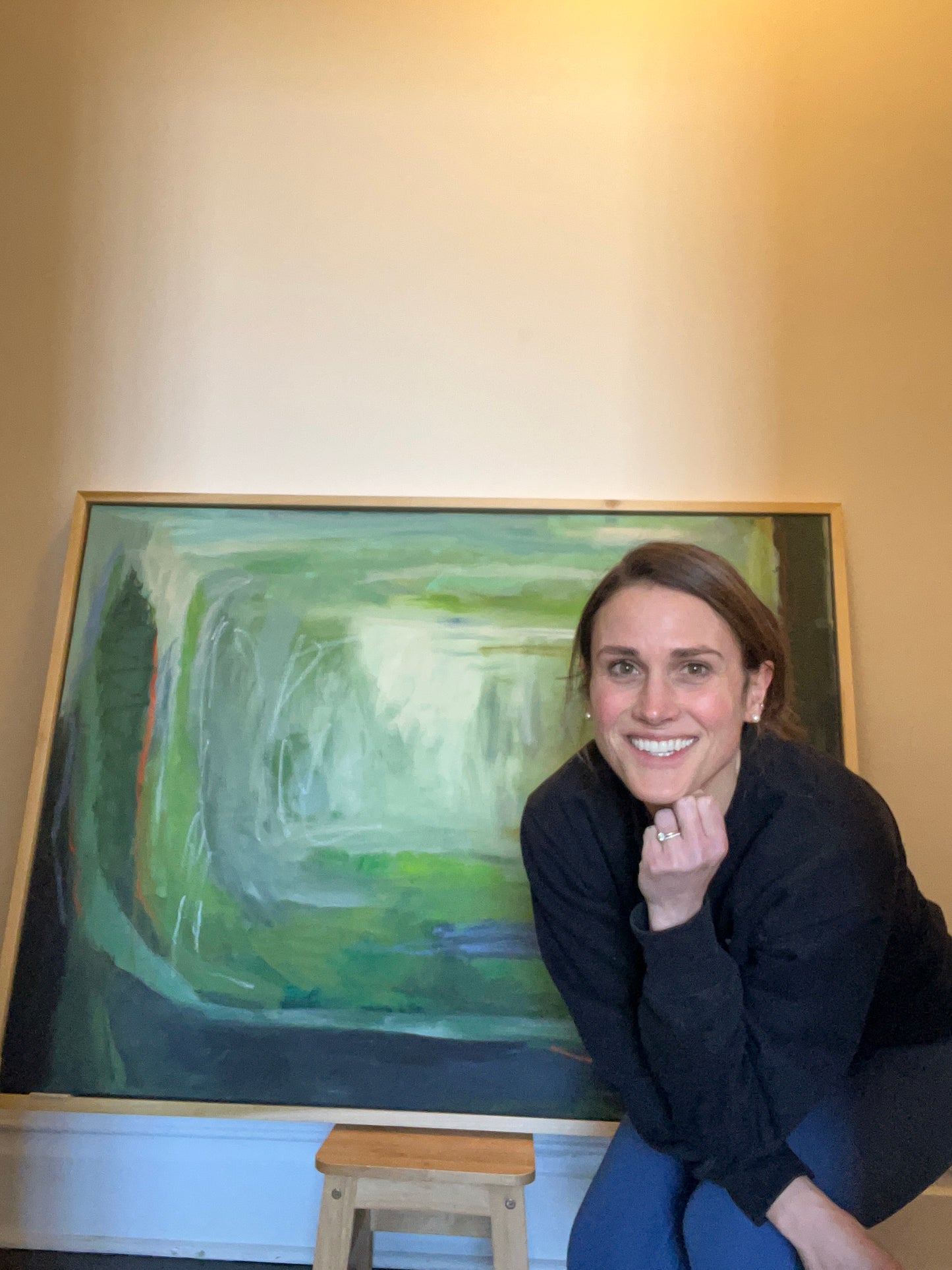 Woman standing next to a painting with a smile on her face