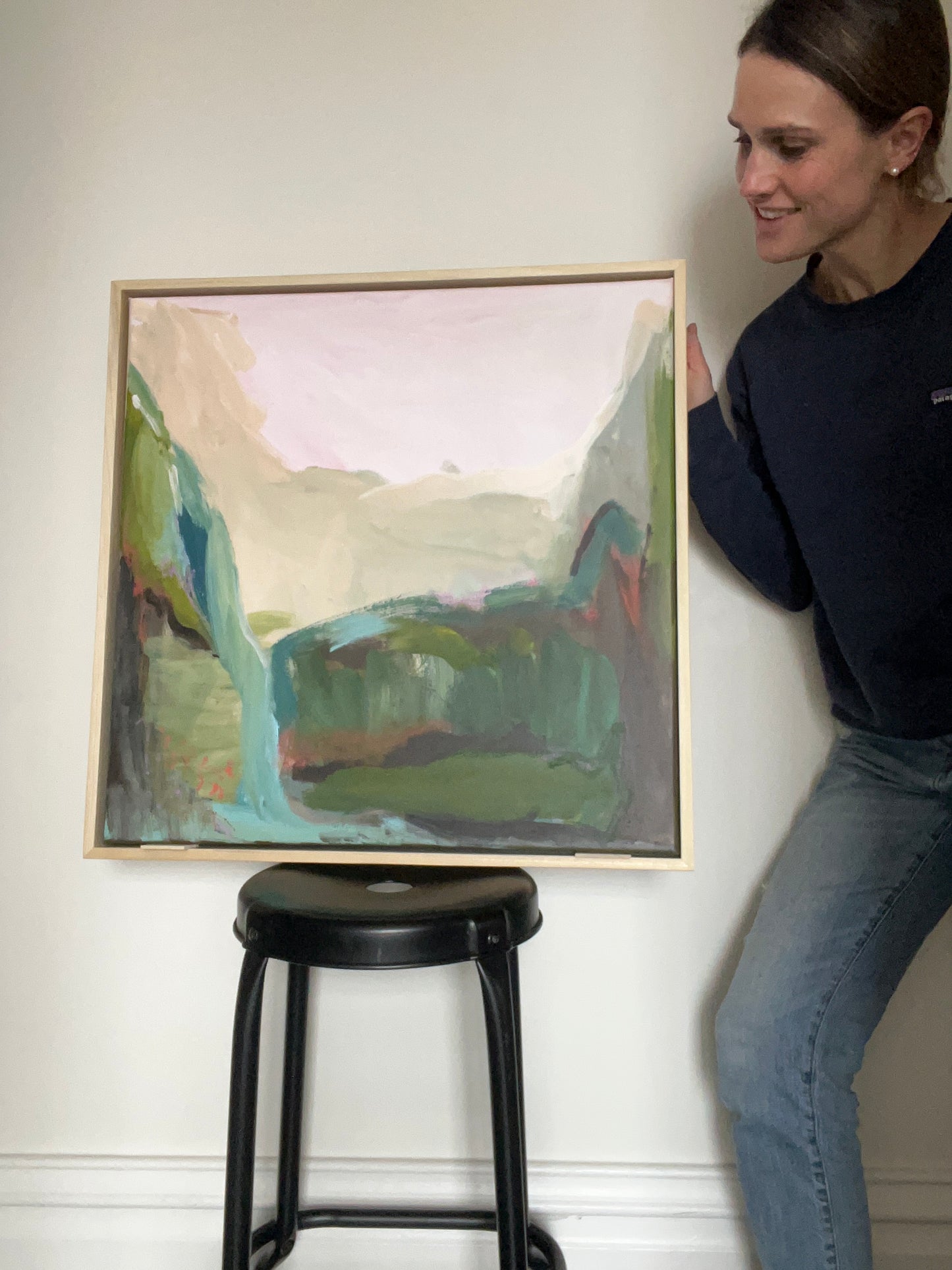 Person lying on floor looking at a framed abstract painting