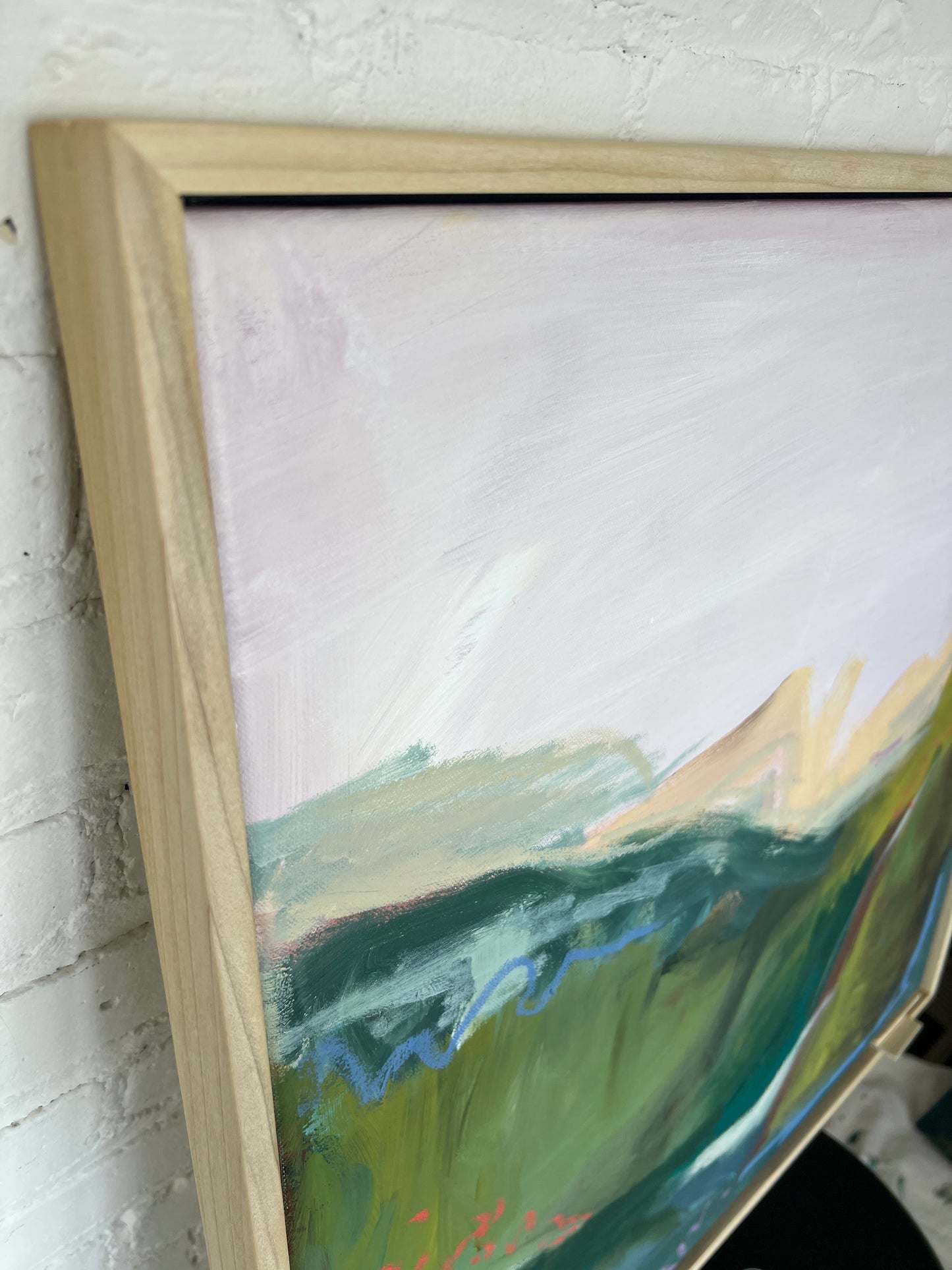 Close-up of a framed abstract painting with a wooden frame.